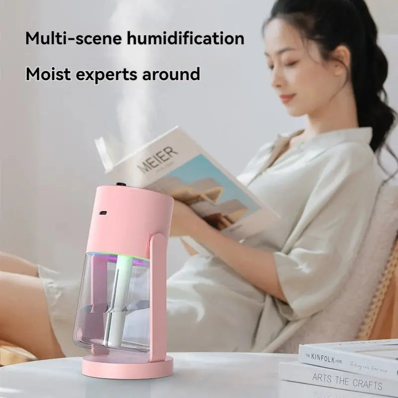 The humidifier on a table next to a girl sitting and reading book 